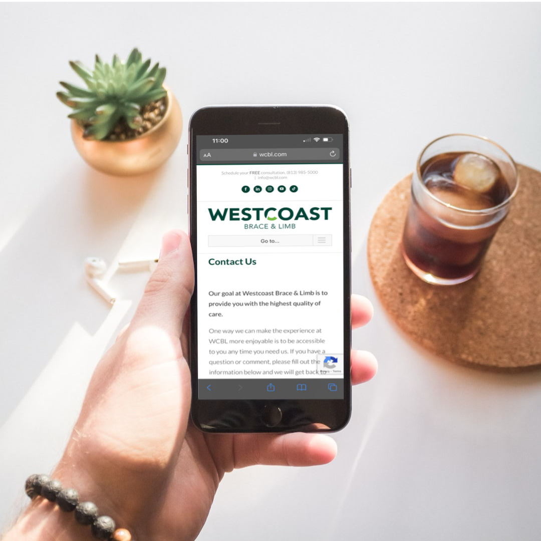 person's hand holding a phone showing the contact us page on the westcoast brace and limb website